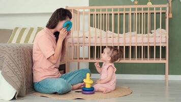 kinderopvang Bij huis, kind bescherming, nieuw leven, vrije tijd met baby. mam en dochter Speel speelgoed Bij huis terwijl zittend Aan de verdieping in de slaapkamer video