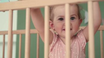 kinderopvang Bij huis, kind bescherming, nieuw leven, vrije tijd met baby. de kind looks uit van de wieg en lacht video