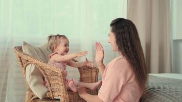 puericultura às lar, criança proteção, Novo vida, lazer com bebê. mãe tocam com dela bebê palmas dela mãos às casa video