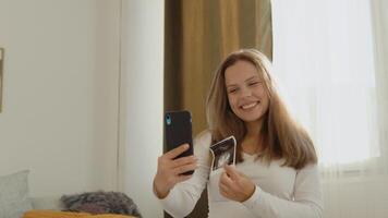 Pregnant woman shows the interlocutor a photo from the ultrasound examination of the fetus using a video link on a smartphone