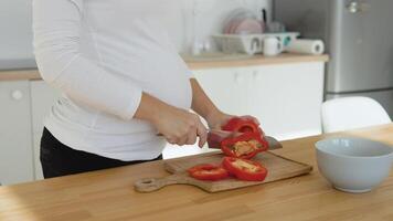embarazada mujer en el cocina cortes rojo pimienta. sano equilibrado dieta durante el embarazo video