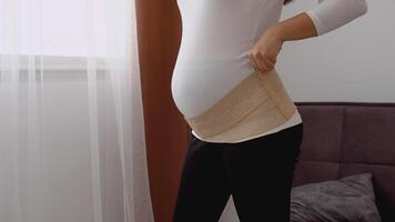 Pregnant fair-skinned woman wears a bandage for pregnant women video