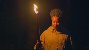 Jeune africain femme avec frisé cheveux explorant foncé nuit avec torche lumière video