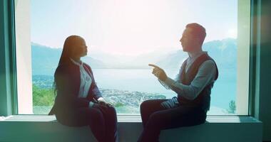 Two young business people talking together inside modern office lobby video