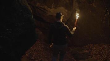 Man Holding A Burning Torchlight Exploring Forest Cave Landscape In Dark Night video