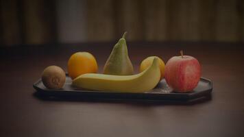 fruit assortiment van banaan, Peer, oranje, appel en kiwi weergegeven Aan een tafel video