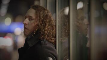 Curlyhaired man poses in contemplative mood by glass door in various settings video