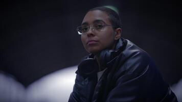 A woman in glasses and headphones sits in a dark room video