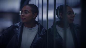 A woman in electric blue glasses stands before a mirror for a vision care event video