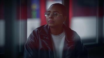 A woman with eyewear and leather jacket sits by window video