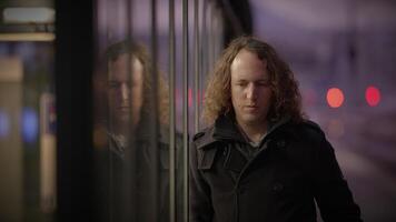 a man with long curly hair is standing in front of a train video