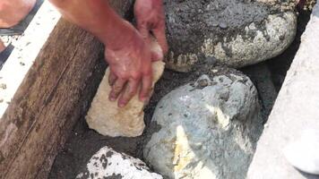 Construction, Worker Hands smooth wet cement in wooden frame at a construction site during daytime to ensure an even surface video