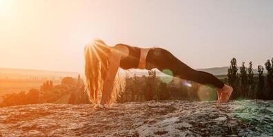 Fitness woman. Happy middle-aged fitness woman doing stretching and pilates on a rock near forest at sunset. Female fitness yoga routine. Healthy lifestyle with focus on well-being and relaxation. photo