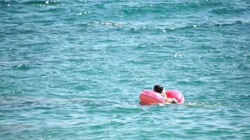 Sommer- Ferien Frau schwimmt auf ein aufblasbar Krapfen Matratze, ein Wasser Spielzeug schwimmen Ring. positiv glücklich Frau entspannend und genießen Familie Sommer- Reise Ferien Ferien auf das Meer. schleppend Bewegung video