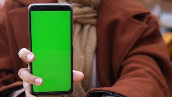 Close up of young woman hand showing smart phone with green screen video