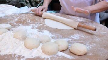 Hand rolling dough with rolling pin on wooden table video