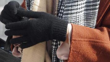 woman hands put on warm gloves on a winter cold day, video