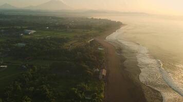 Aerial view of scenic Bali ocean coastline and Agung volcano with warm sunrise or sunset tones video