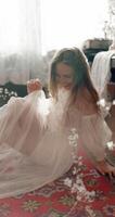 jung elegant Modell- tragen Jahrgang Braut- Kleid Sitzung auf Boden, posieren beim Zuhause im stilvoll Jahrgang Innere video