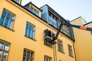 Two mechanic man on hydraulic crane with repairing window photo