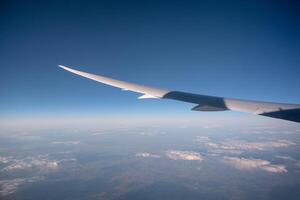 Wing of airplane flying above in blue sky on sunny day photo