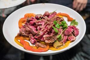 Beef steak sliced with tomato and potato on white plate photo