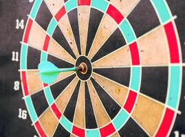 Dart in bullseye center of target on aged dartboard photo