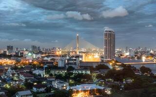 paisaje urbano de rama 8 puente terminado el chaophraya río con edificios brillante a oscuridad foto