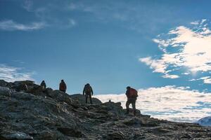 Group of backpacker hiking on summit in daylight at Swiss Alps photo