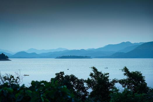 Blue scene of the Kaeng Krachan reservoir with fishing boat and tourist rowing canoe photo