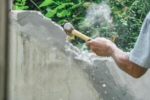 Hand of worker using hammer smashing and demolish on brick wall at construction site photo