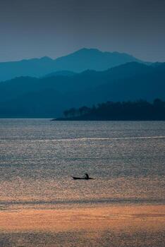 Sunset view of the Kaeng Krachan reservoir with fishing boat and tourist rowing canoe photo