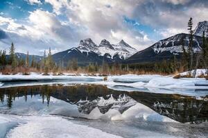 Three Sisters Mountains with snow covered on frozen bow river reflection in the morning on winter photo