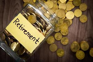 Coin glass jar container on wooden desk, retirement saving concept photo