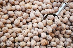 A scoop of walnuts, a superfood, rests on a stack of nuts seeds photo