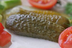 un cerca arriba de un pepinillo en un plato con Tomates foto