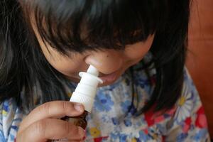 close up of sick child using nasal medicine spray photo