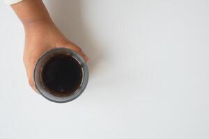 top view of child hand holding a glass of soft drinks on white background photo