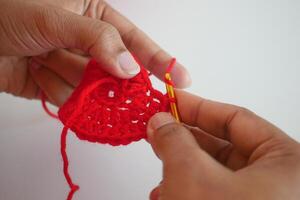 Hand close up crocheting with a pink hook, wool yarn, creative craft photo