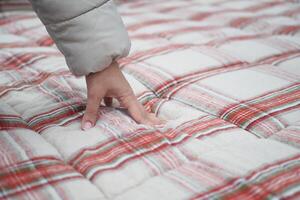 mujer mano conmovedor y prensado ortopédico colchón en cama. foto