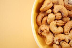 cashew nuts in a small bowl on yellow color background photo