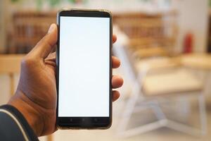 mano de hombre joven usando un teléfono inteligente con pantalla blanca en el café foto