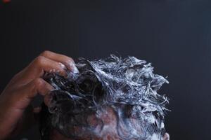 young men washes h his hair with shampoo . photo