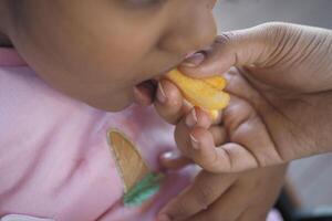 niño comiendo francés papas fritas cerca arriba foto