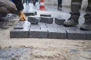 a worker laying concrete bricks on each other for building a new sidewalk photo