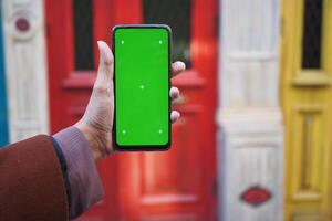 Person holding an smart phone against colorful wood doors photo