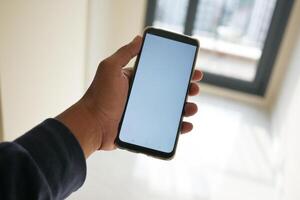 pov de mano utilizando teléfono demostración blanco pantalla en vacío habitación foto