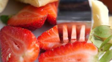 vork plukken rijp rood aardbeien in een kom Aan tafel video