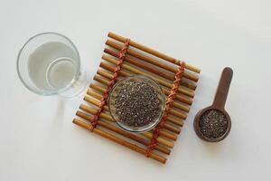 top view of chia seed in a container and glass of water on table photo