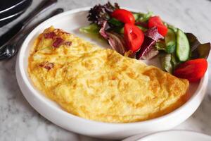 llanura huevo tortilla y hierbas en un plato en mesa foto